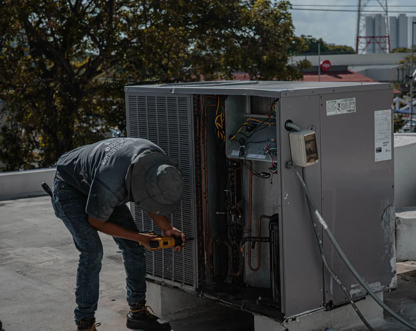 Técnico dando servicio a una unidad de aire acondicionado comercial en un techo
